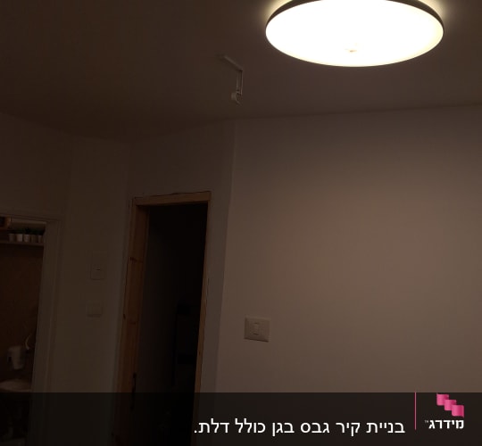 קיר גבס עם מתג תאורה ודלת עץ